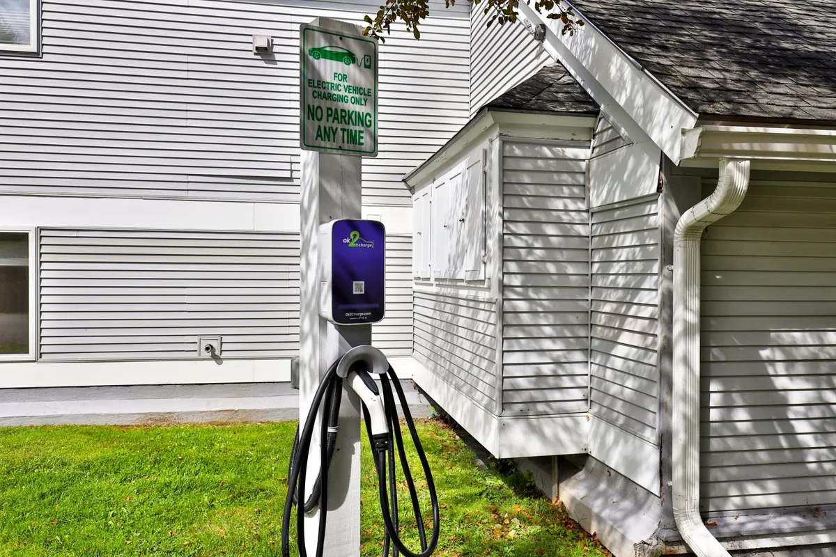 An exterior view highlighting the Swirl Suite Annex’s electric vehicle charging station, alongside signage indicating parking details. The modern amenities and convenient access complement the eco-friendly and contemporary experience.