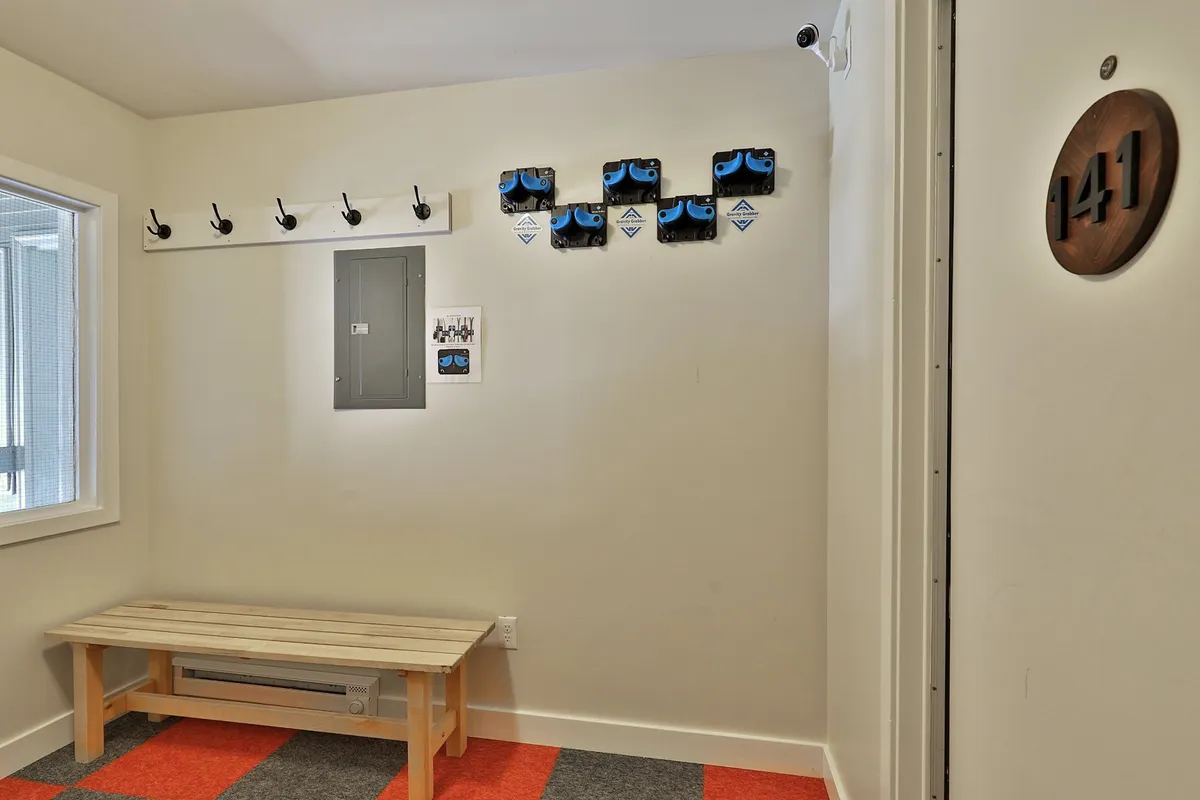 An organized, functional entryway with wall hooks, a bench, and mounts for equipment, ideal for storing winter gear after a day on the slopes. The space feels welcoming and practical, reflecting the transition from outdoor adventures to cozy relaxation inside.