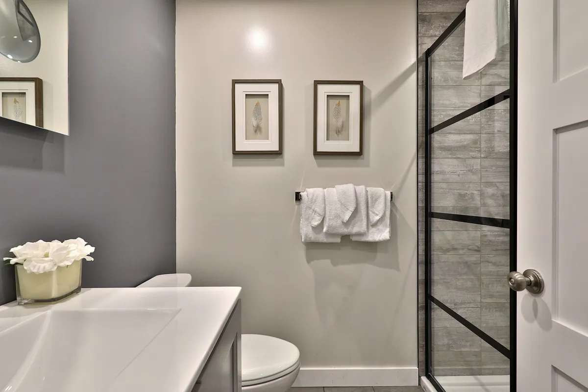 A serene bathroom featuring a modern sink, a shower enclosure, framed artwork, and neatly arranged plush towels. The atmosphere is calm and inviting, ideal for relaxation after an active day.