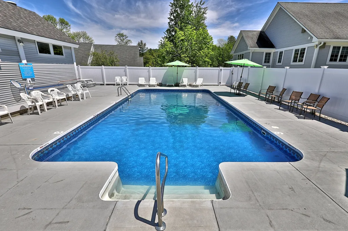 An inviting outdoor swimming pool with lounge chairs and umbrellas is the focal point, surrounded by manicured landscaping. The vibe is leisurely, perfect for relaxing after an active day outdoors.